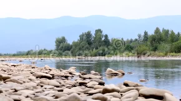 山河的水流它平静地在山谷中流动可见的石头在河岸上在地平线上视频的预览图