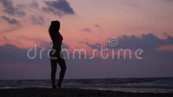 穿着泳衣的女人在海边享受日落视频的预览图