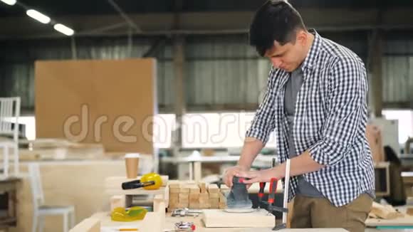 年轻的木工在工作台的车间里使用抛光机视频的预览图