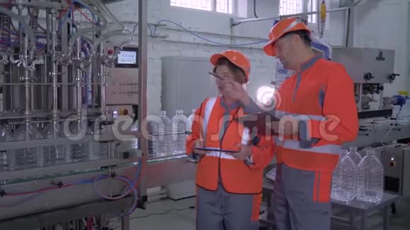 幸福工厂工人的肖像男女工人戴着头盔穿着工作服靠近输送线附近手里拿着药片视频的预览图