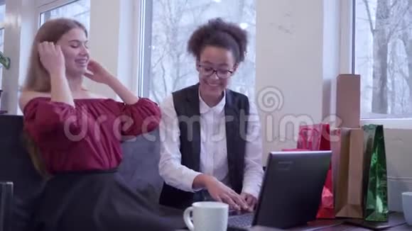 网上购物微笑的多民族朋友女孩用塑料卡和笔记本电脑进行网上购物视频的预览图