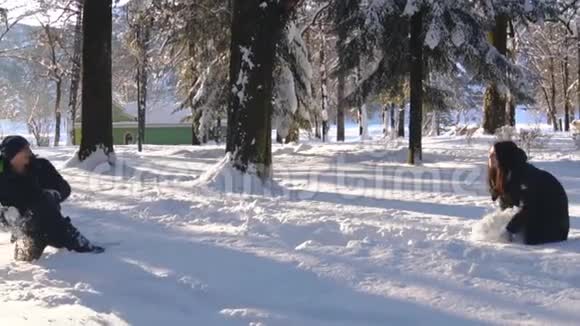 在冬天的森林里打雪仗和玩雪乐的快乐夫妻视频的预览图