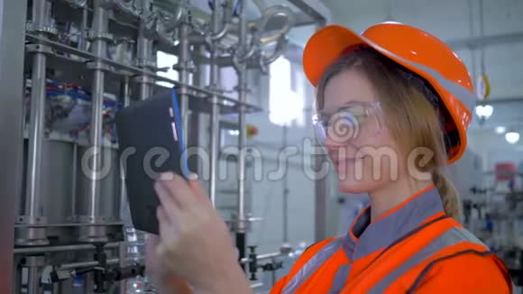 女工程师在工作时年轻的工厂技术人员女士戴着安全帽使用电脑平板电脑并进行计算视频的预览图