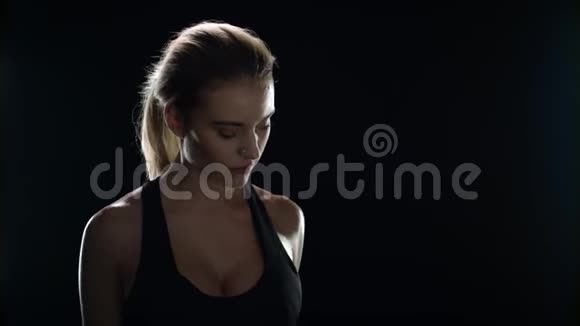 健身女性举重哑铃和寻找相机在黑色背景视频的预览图