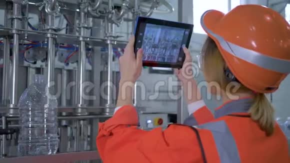 工厂专业女安全帽工程师使用平板电脑为工厂扫描设备制作照片视频的预览图