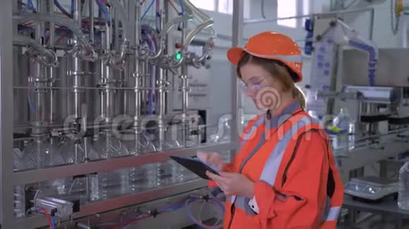 工厂工程师女进入头盔使用数字平板控制装瓶用水的皮带线的工作视频的预览图
