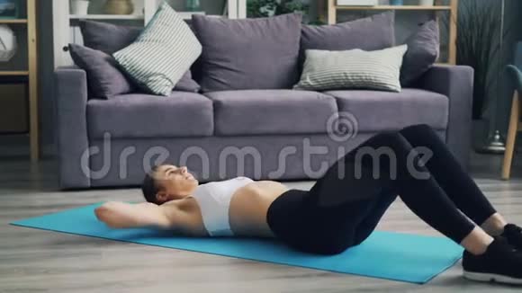 漂亮的女孩在家里的垫子上进行个人体育锻炼视频的预览图