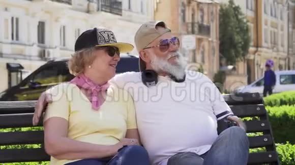 在城市的长椅上放松的快乐时尚老人的画像视频的预览图