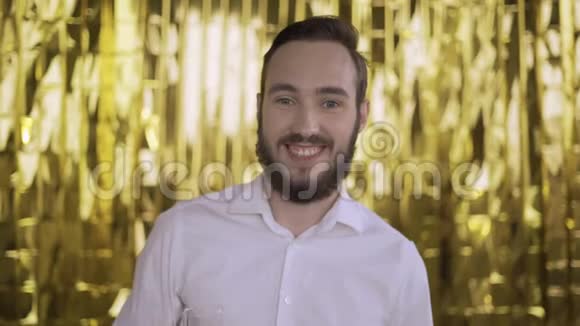 金色背景上的一个年轻人的肖像男人微笑着拿出一罐香槟视频的预览图