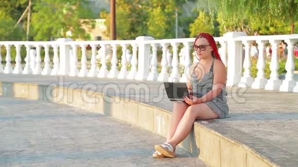 年轻的晒黑的女性博客写手在长廊上用笔记本电脑工作视频的预览图