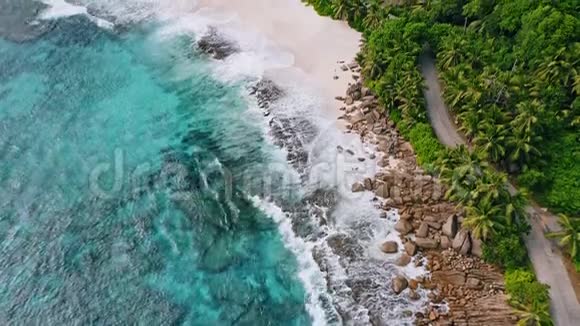 在马河的AnseBazarca海浪拍打着岩石和白色海滩周围是椰子树视频的预览图