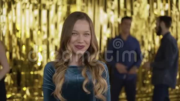 金色背景上一个年轻迷人的女孩的肖像在聚会上穿着漂亮绿色连衣裙的女孩4K视频的预览图