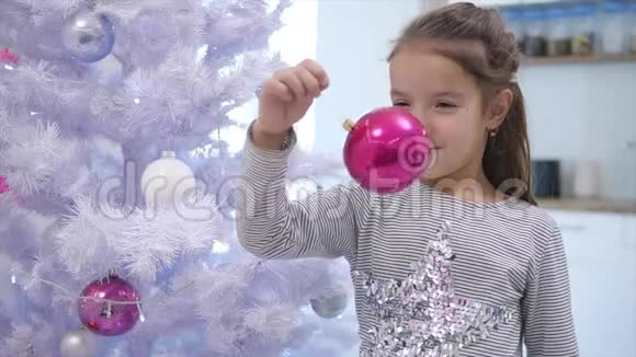 可爱的孩子玩一个粉红色的宝布尔左右摇摆站在圣诞树附近微笑视频的预览图
