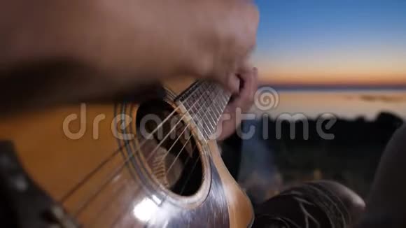 晚上在篝火旁男性手弹吉他视频的预览图