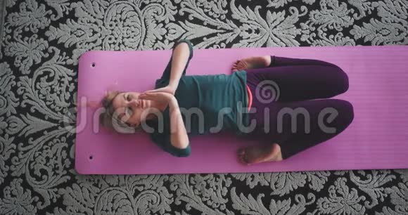 冥想时间女士在家里在垫子上练习瑜伽从高处捕捉视频女士做瑜伽练习视频的预览图