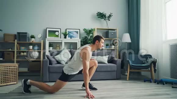 穿运动装的漂亮小伙子在家做运动伸伸腿视频的预览图
