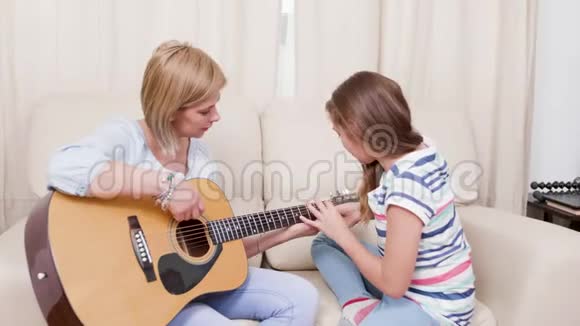 妈妈和女儿在客厅里学着吉他演奏视频的预览图