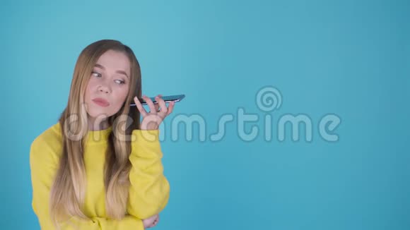 拍摄于欧洲的一位成年女性在扬声器上与它交谈时嘴边握着电话站在蓝色的旁边视频的预览图