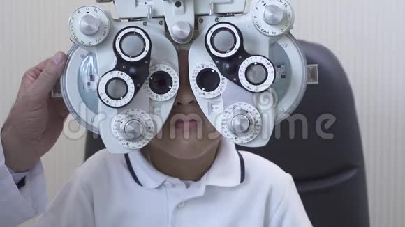 眼科门诊视光师对男性患者进行光镜检查非裔美国男孩做眼睛测试慢慢视频的预览图