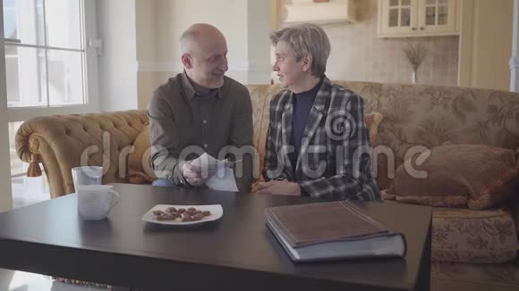快乐的老夫妇坐在家里互相交谈家庭关系慢动作视频的预览图