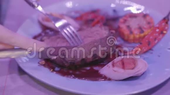 这个女孩手切一大块肉在现代餐馆里享受她的晚餐甜玉米辣椒和视频的预览图