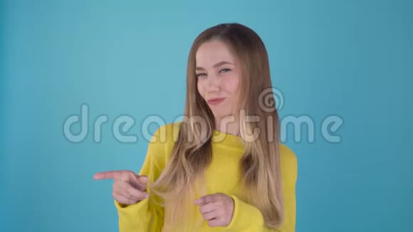 哦对了这个和这个穿着黄色毛衣的可爱有趣的女孩在不同的侧面展示了她的手指孤立的蓝色视频的预览图