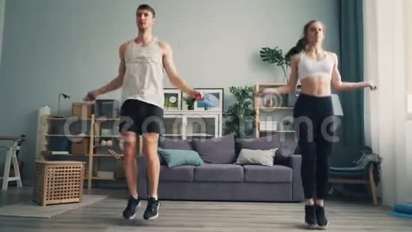 有魅力的女孩和男人在工作室公寓里跳绳专注于锻炼视频的预览图