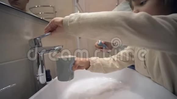 儿童口腔卫生可爱的小女孩刷牙用干净的自来水冲洗洗手池上的嘴视频的预览图