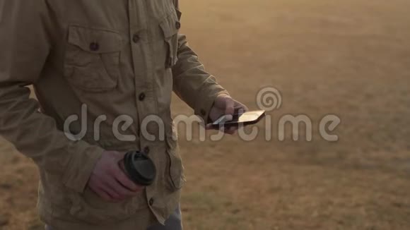 用手机关闭室外的人并滚动磁带喝咖啡的人太阳在屏幕上发光视频的预览图