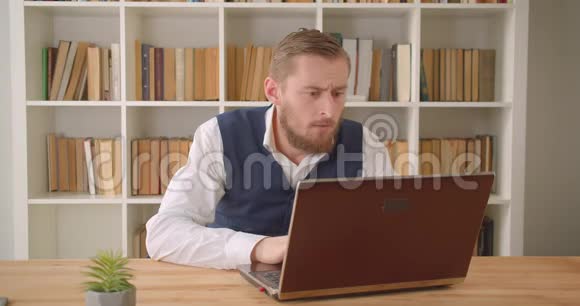 用笔记本电脑拍摄的白种人年轻商人的特写照片由于办公室的错误而沮丧视频的预览图