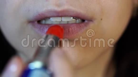 女人画她的嘴唇特写宏观拍摄女人用红色口红涂嘴唇女性面部嘴巴特写视频的预览图
