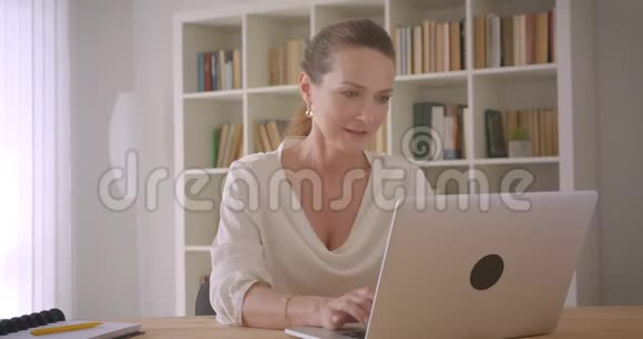 用笔记本电脑拍摄的白种人深色头发的老女商人的特写镜头镜头里洋溢着幸福的笑容视频的预览图