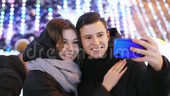 快乐的一对情侣在现代手机上自拍在新年之夜微笑亲吻视频的预览图