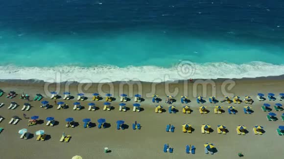 在希腊绿松石海的海岸上有雨伞和日光浴床的海滩在群岛度假罗兹视频的预览图