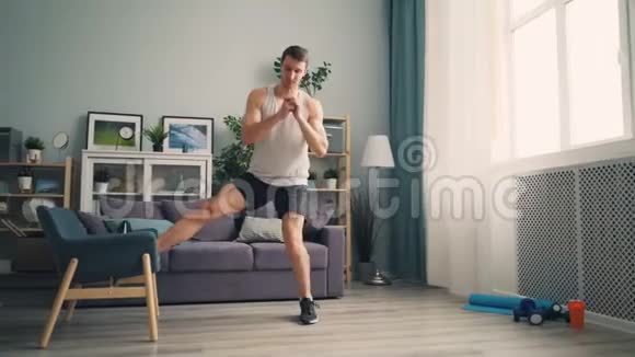 帅哥运动员在公寓里用扶手椅蹲着享受运动视频的预览图