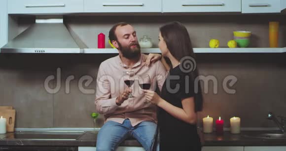 一对夫妇在家里的现代厨房有一个浪漫的时间喝红酒和聊天视频的预览图