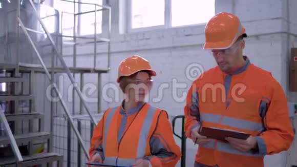 工厂专家女孩带着戴着平板电脑头盔的男人正在检查生产同时讨论质量问题视频的预览图