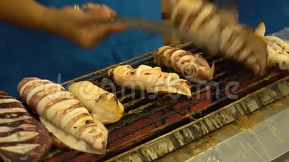 在夜间食品市场街头食品的烤架上烤制或烤制鱿鱼视频的预览图
