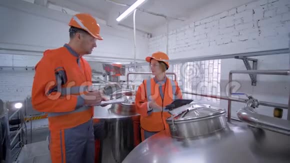 在讨论质量问题时工厂工程师女士带着带笔记本电脑的男性头盔检查工厂视频的预览图
