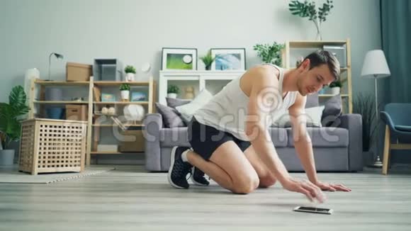 帅哥在家锻炼用智能手机在木板上做有氧运动视频的预览图