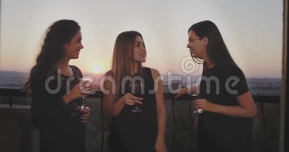 漂亮的三位女士在阳台的顶层举行一个女孩聚会她们喝一些玻璃酒还有一个视频的预览图
