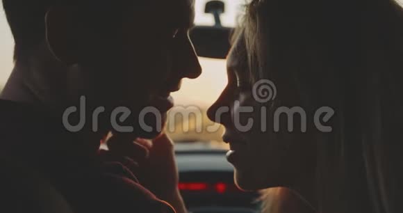 一对夫妇在阳光下的剪影在一个吻之前在车里的大角度视频的预览图