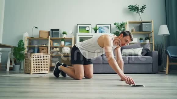 运动员触摸智能手机屏幕然后在家练习木板位置视频的预览图