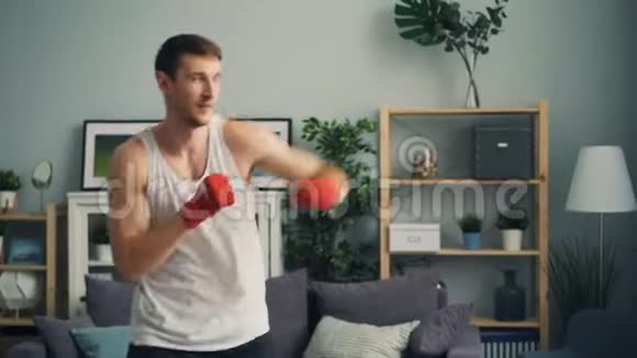 一个运动装拳击的肌肉男独自待在公寓里享受活动视频的预览图