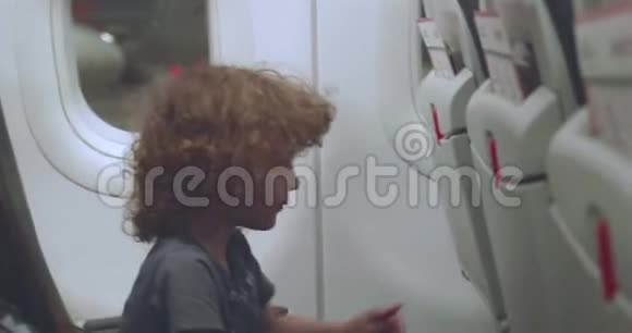 小男孩试图调整他的座椅靠背在飞机上视频的预览图