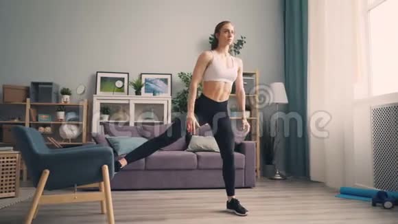 漂亮的年轻女运动员在家里用扶手椅锻炼身体视频的预览图
