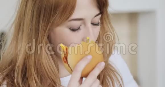 年轻微笑的女人吃汉堡的肖像视频的预览图