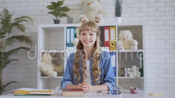 快乐的女孩对观众微笑成功的女学生在餐桌上4K视频的预览图