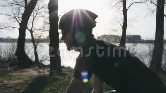 近距离观看骑自行车时留着胡须的骑车人饮水阳光透过树木照射反射头盔和太阳镜视频的预览图