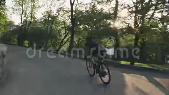 瘦小的运动骑自行车的人在公园里骑公路自行车骑着黑色自行车的骑自行车者穿着黑色的衣服自行车的概念视频的预览图